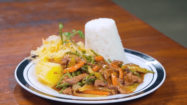 A plate of rice with stir-fried beef and vegetables