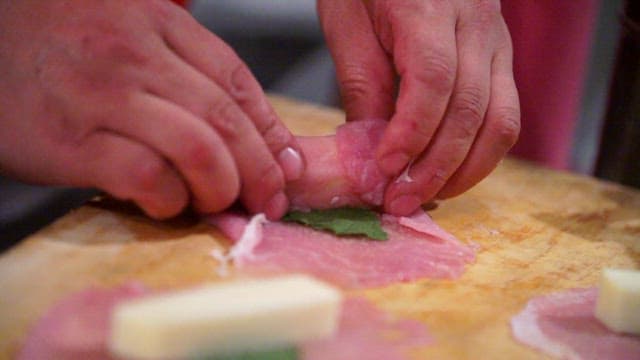 Rolling the meat around the cheese on a cutting board