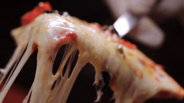 Close-up of a hot, cheesy pizza slice being lifted
