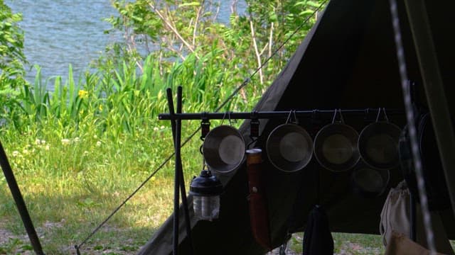 Camping site by a lake with utensils hanging inside the tent