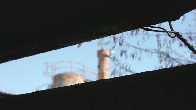 Rusty structures of industrial facilities visible through small gaps