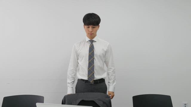 Office worker putting on a suit jacket in a conference room