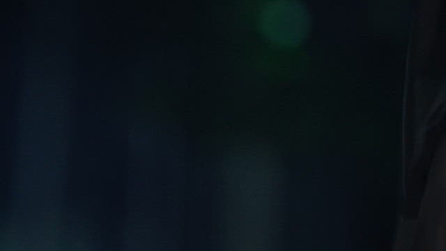 Hands Crumpling 100 Dollar Bills in the Dark