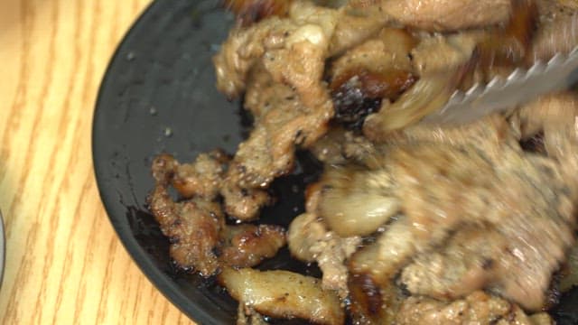 Grilled appetizing pork bulgogi being served on a black plate