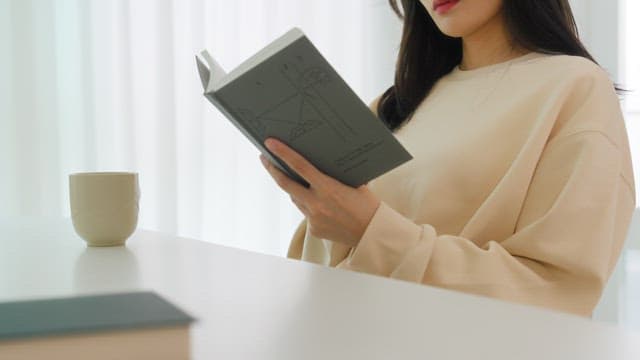 Woman Reading a Book While Drinking Coffee