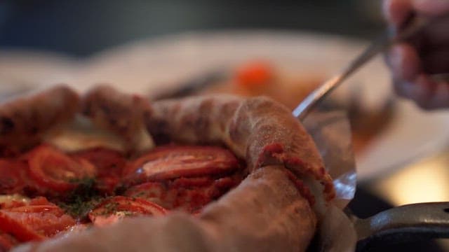 Cheese pizza slice being lifted with a fork at a table