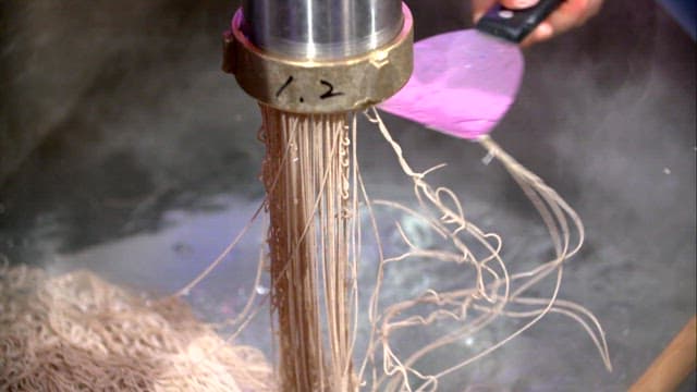 Noodles being extruded into boiling water