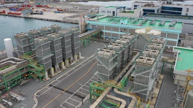 Industrial plant near a dock with cooling towers and pipelines