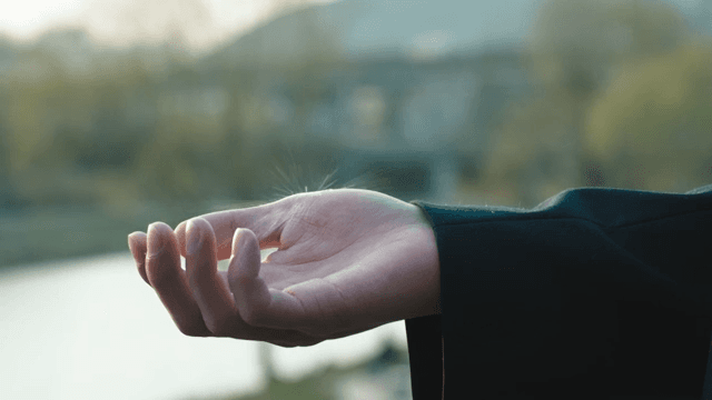 Hand reaching out to falling raindrops