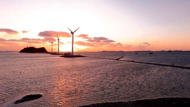 Wind turbines by the sea at sunset