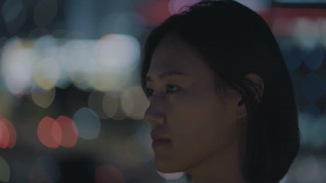 Contemplative woman amidst city lights at night