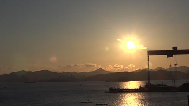 Scenic view of a coastal industrial area with the sun setting