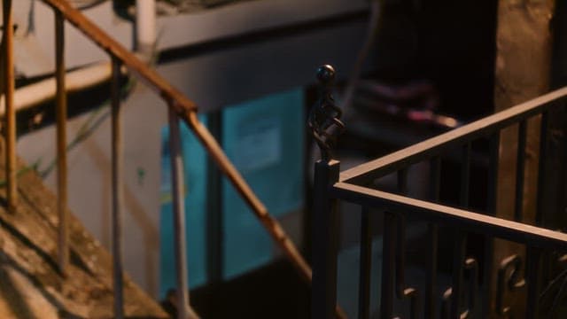 Rusty railing and basement entrance illuminated by street lamps