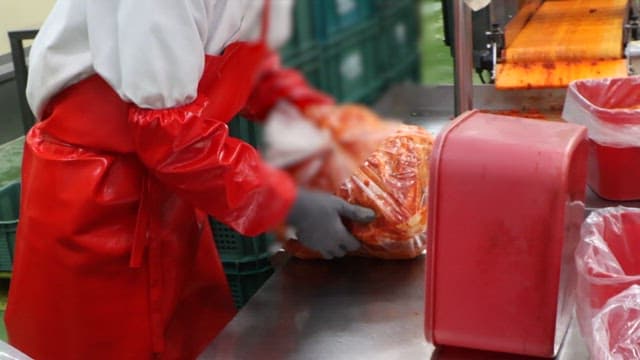 Worker moving packaged kimchi at a food factory