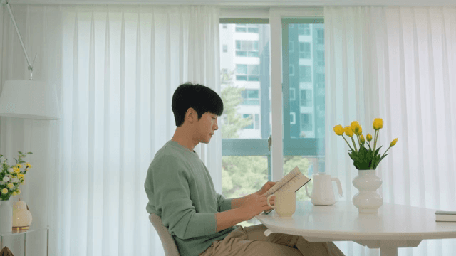 Man Reading a Book by the Window in Bright Living Room