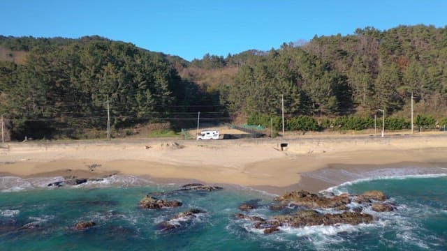 Camper Van Driving by the Serene Beach, Surrounded by Lush Pine Forests
