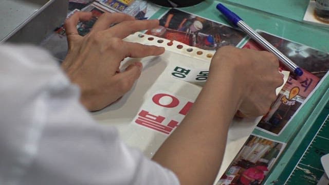 Carefully sticking a barbershop text label on a piece of paper at a workbench
