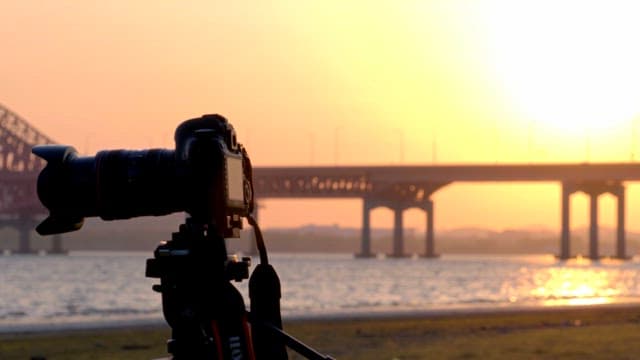 Camera on tripod by the river at sunset