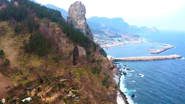 View of a coastal cliff with a rocky landscape and a distant village along the shore
