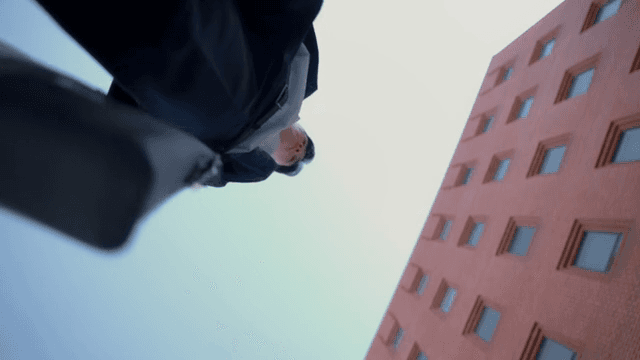Man holding a briefcase standing in front of a red building