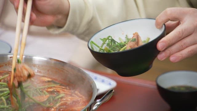 Eating hot pot with fresh water parsley with chopsticks