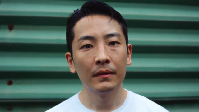 Man standing in front of green wall outdoors