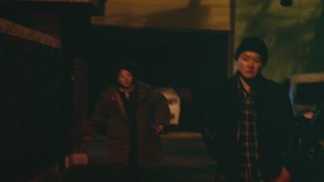 Two individuals talking seriously on a dimly lit street at night