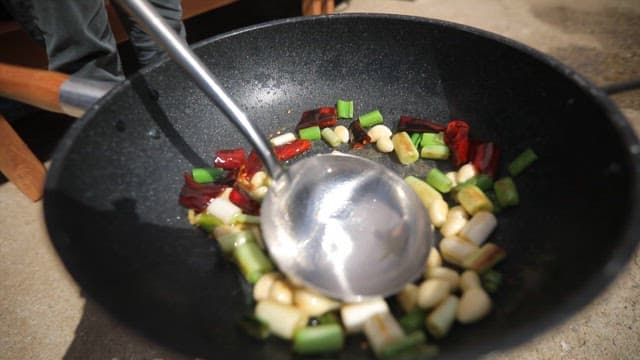Vegetables and meat being stir-fried over high heat in oiled large wok