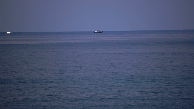Boats sailing on a calm sea at twilight