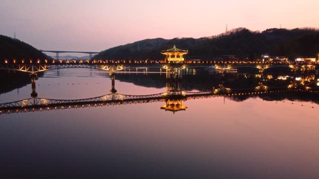 Illuminated bridge over calm river at night