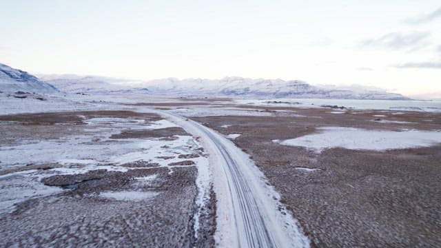 Snowy road winding through a vast mountain landscape