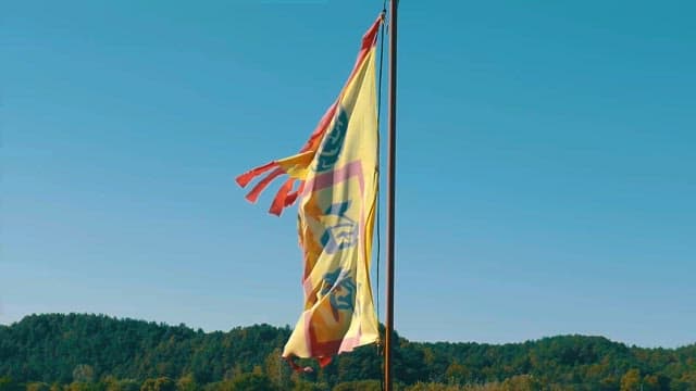 Flag Waving in Front of a Forested Hillside