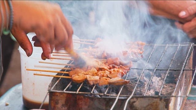 Grilling skewers with sauce on a grill