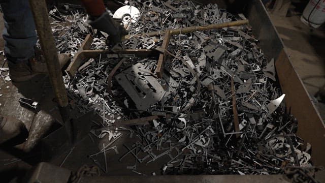 Worker shoveling metal scraps in a factory