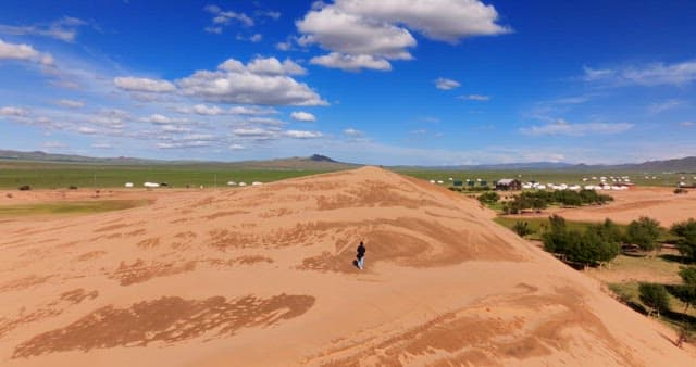 Person walking on a vast sand dune
