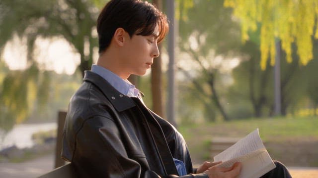 Man reading a book on a park bench