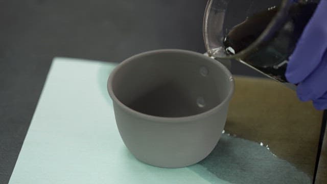Pouring cola from a beaker into a gray cup