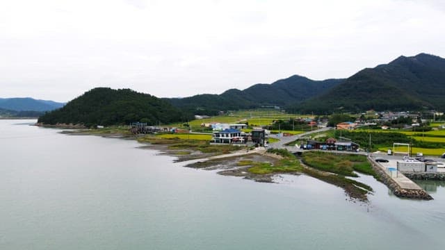 View of a serene coastal village with lush green hills and adjacent farmland