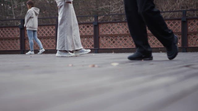 People walking on a wooden deck outdoors in chilly weather