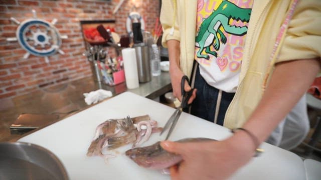 Person cleaning and cutting fish in the kitchen