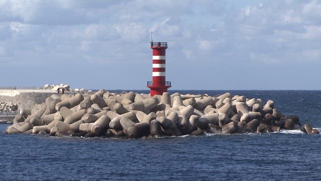 Red and white striped lighthouse on breakwater