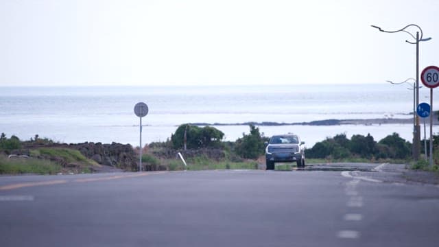 Car driving on an empty coastal road in daylight