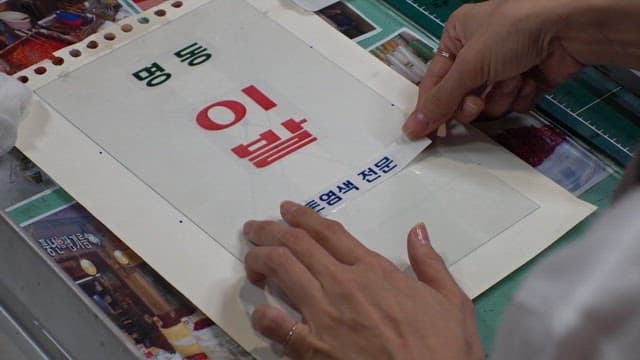 Carefully sticking a barbershop text label on a piece of paper at a workbench