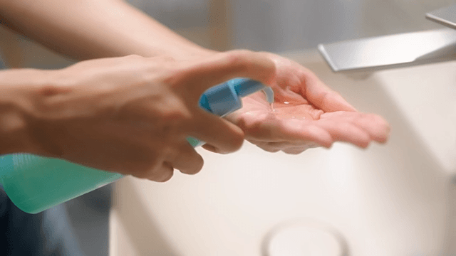 Woman applying cleansing oil to her hands in bathroom