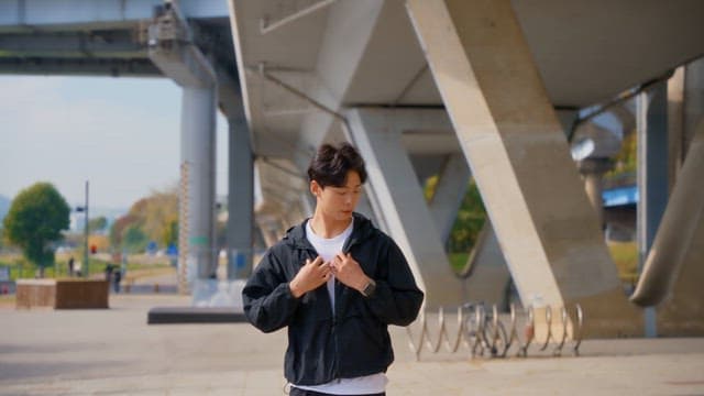 Young man standing under a bridge