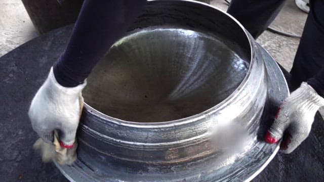 Polishing a freshly made cast iron cauldron