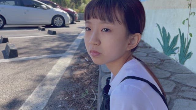 Girl sitting in front of a flower bed in the middle of the day, playing and laughing