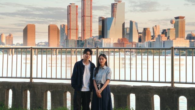 Couple standing by the riverside with cityscape