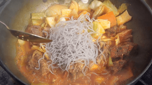 Scene of putting glass noodles in red soup with meat and vegetables