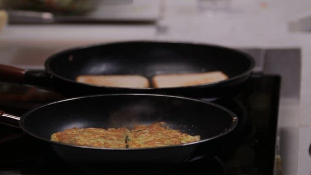 Cooking delicious toast with two frying pans in cozy kitchen